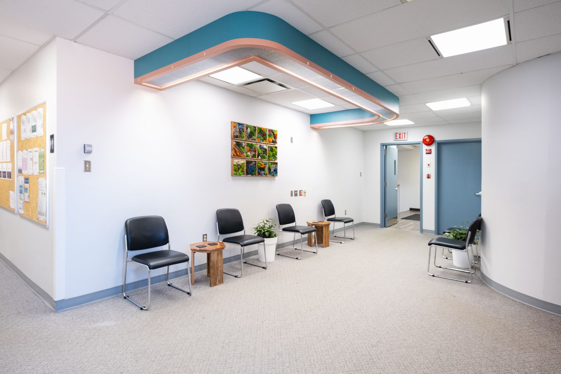 A waiting room with chairs and a bulletin board on the wall.