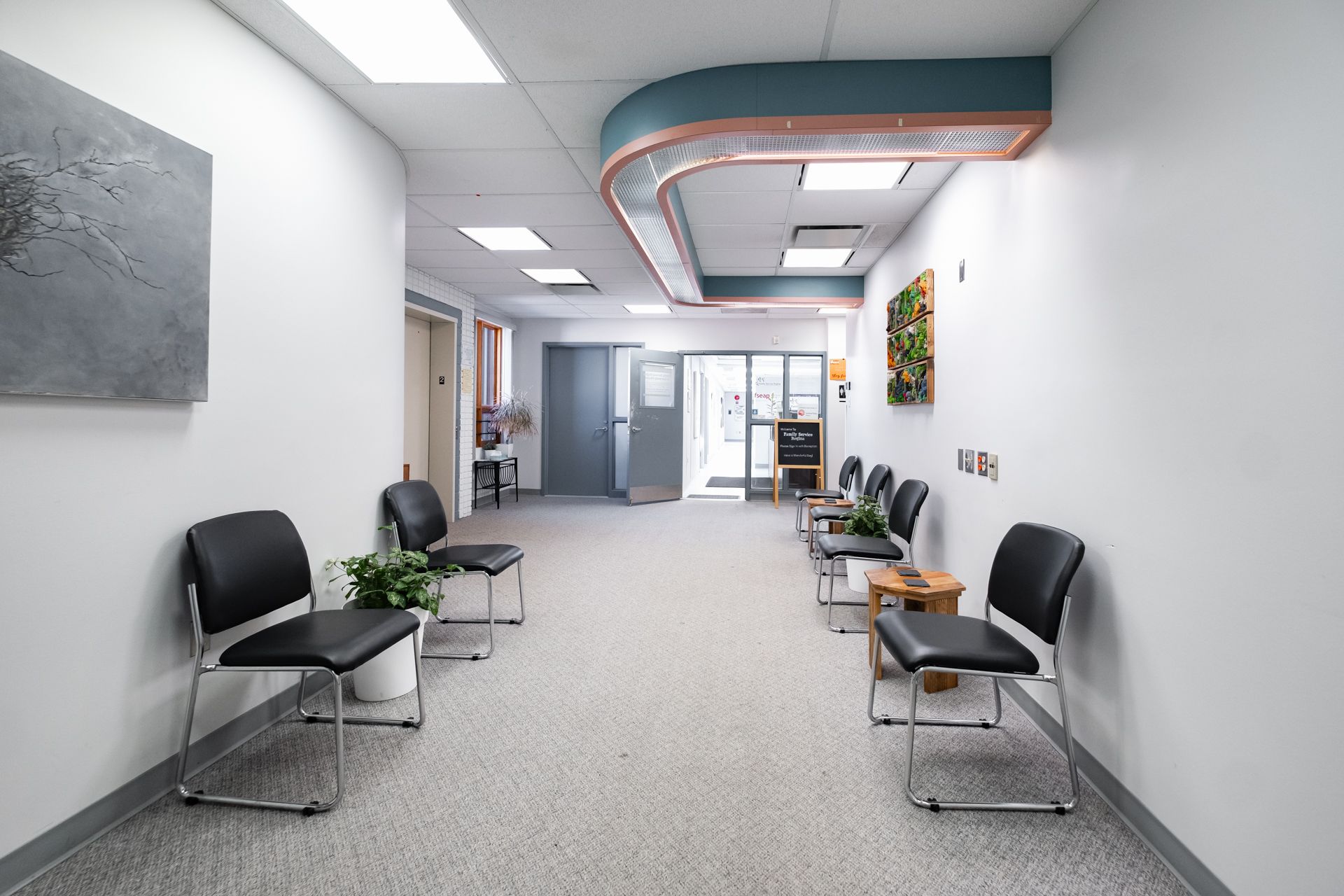 A long hallway with chairs and a painting on the wall.