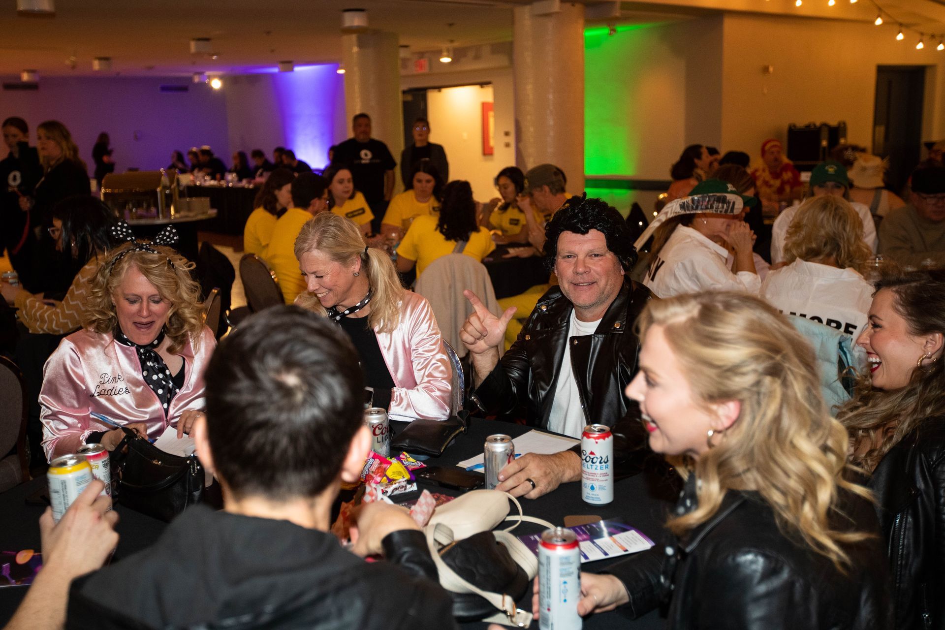 A group of people are sitting around a table with cans of soda.