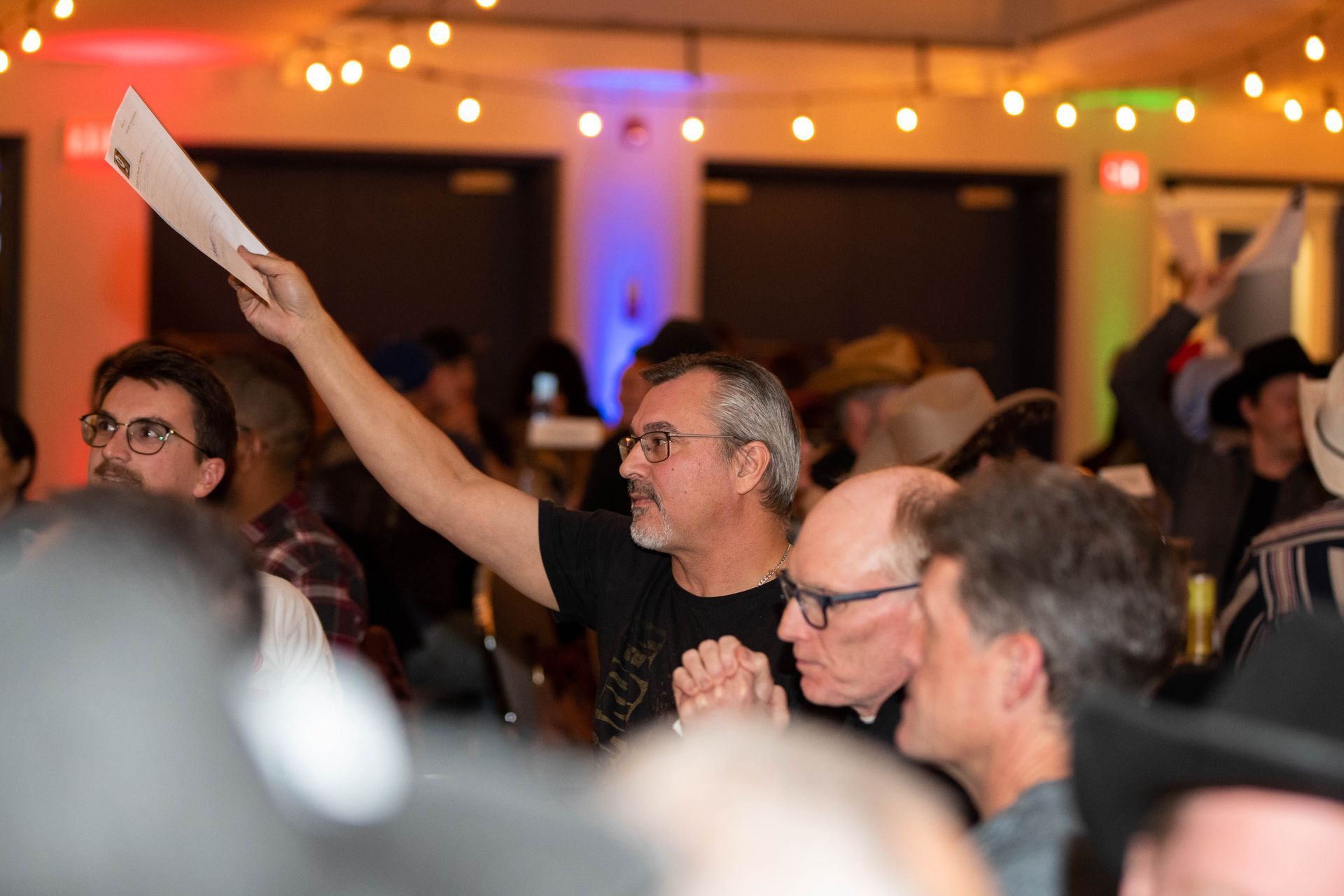 A man is holding up a piece of paper in a crowd of people.