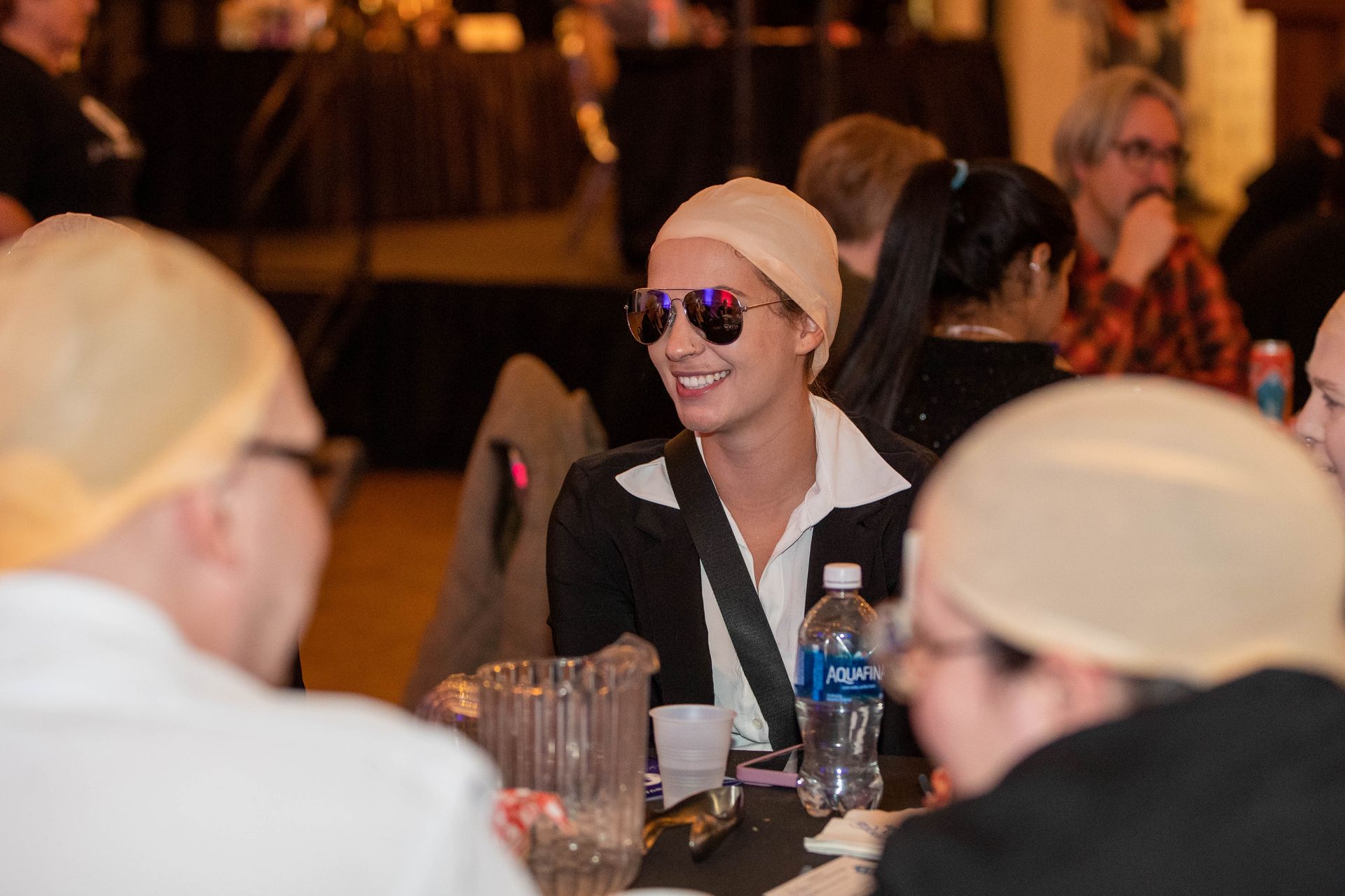 A group of people wearing wigs and sunglasses are sitting at a table.