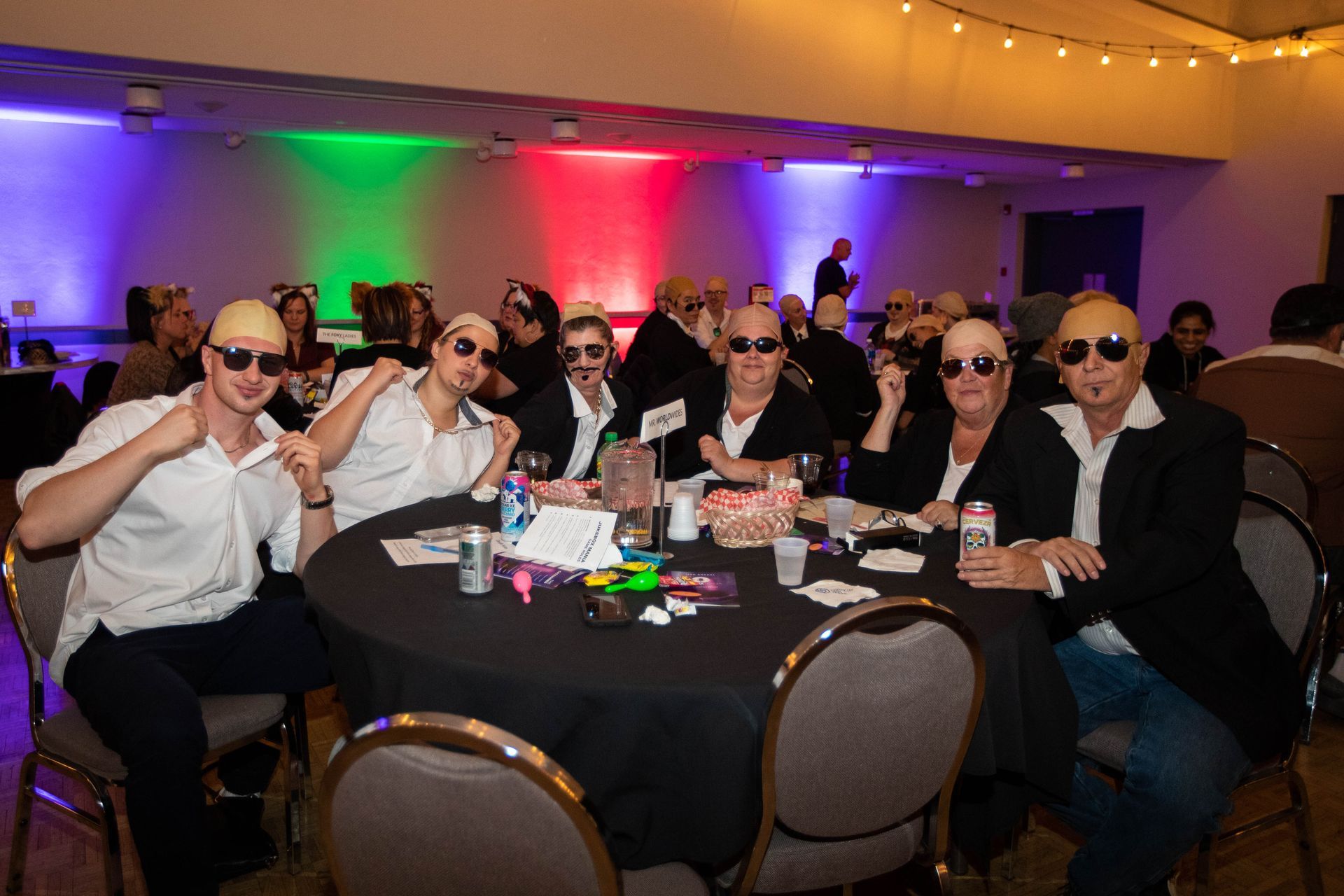 A group of people are sitting at a table wearing sunglasses.