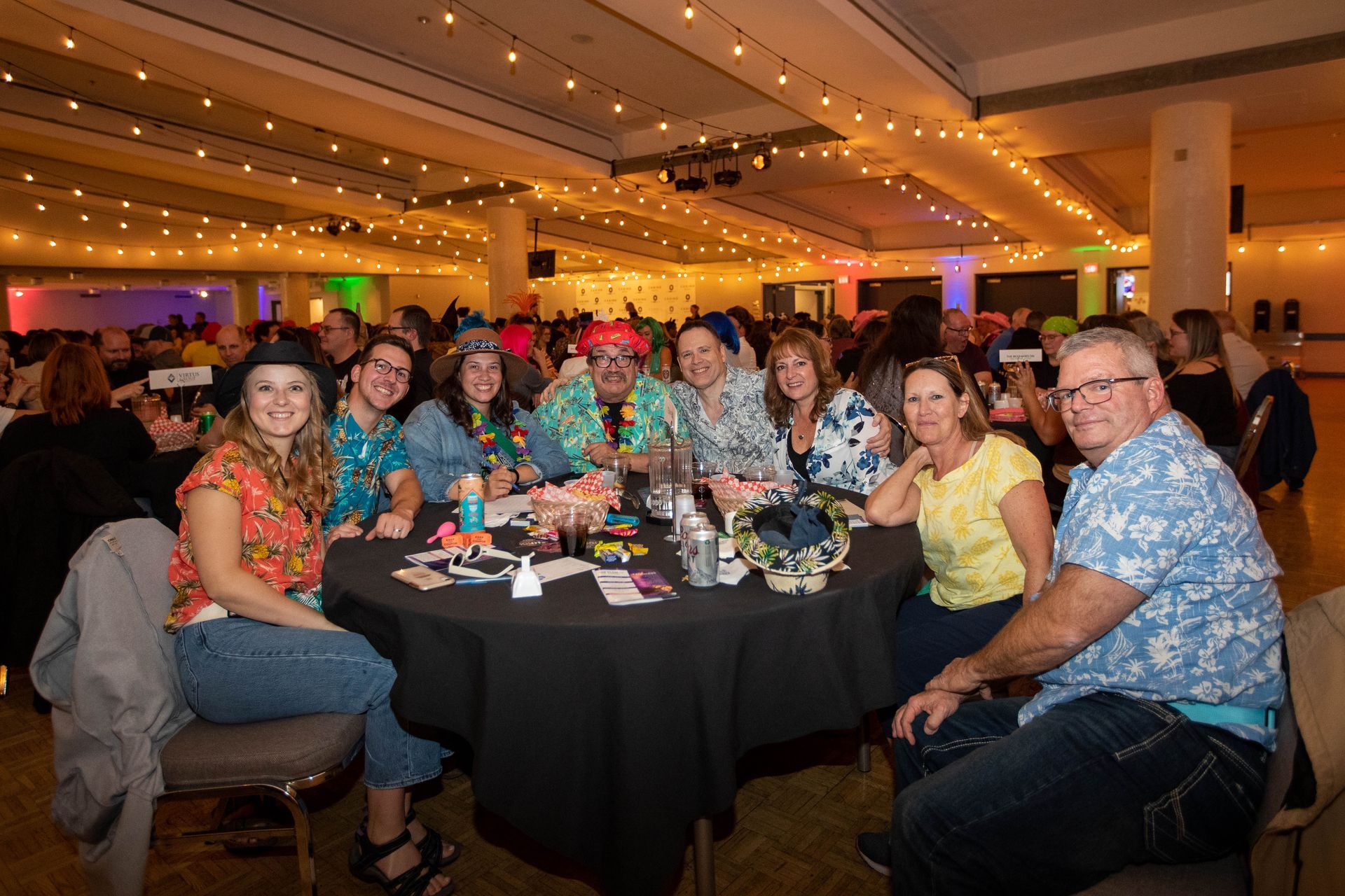 A group of people are sitting at a table in a large room.