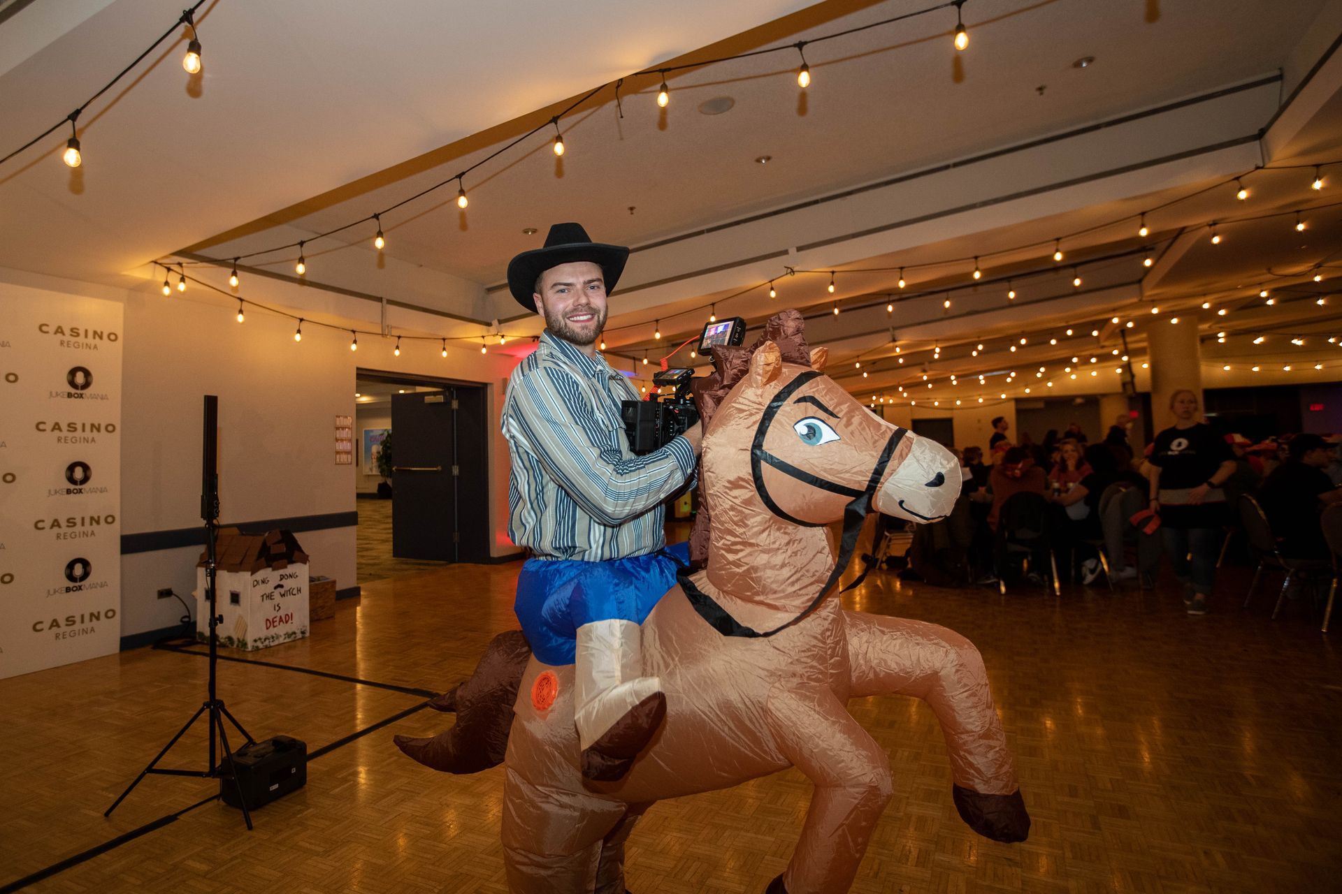 A man in a cowboy costume is riding an inflatable horse.