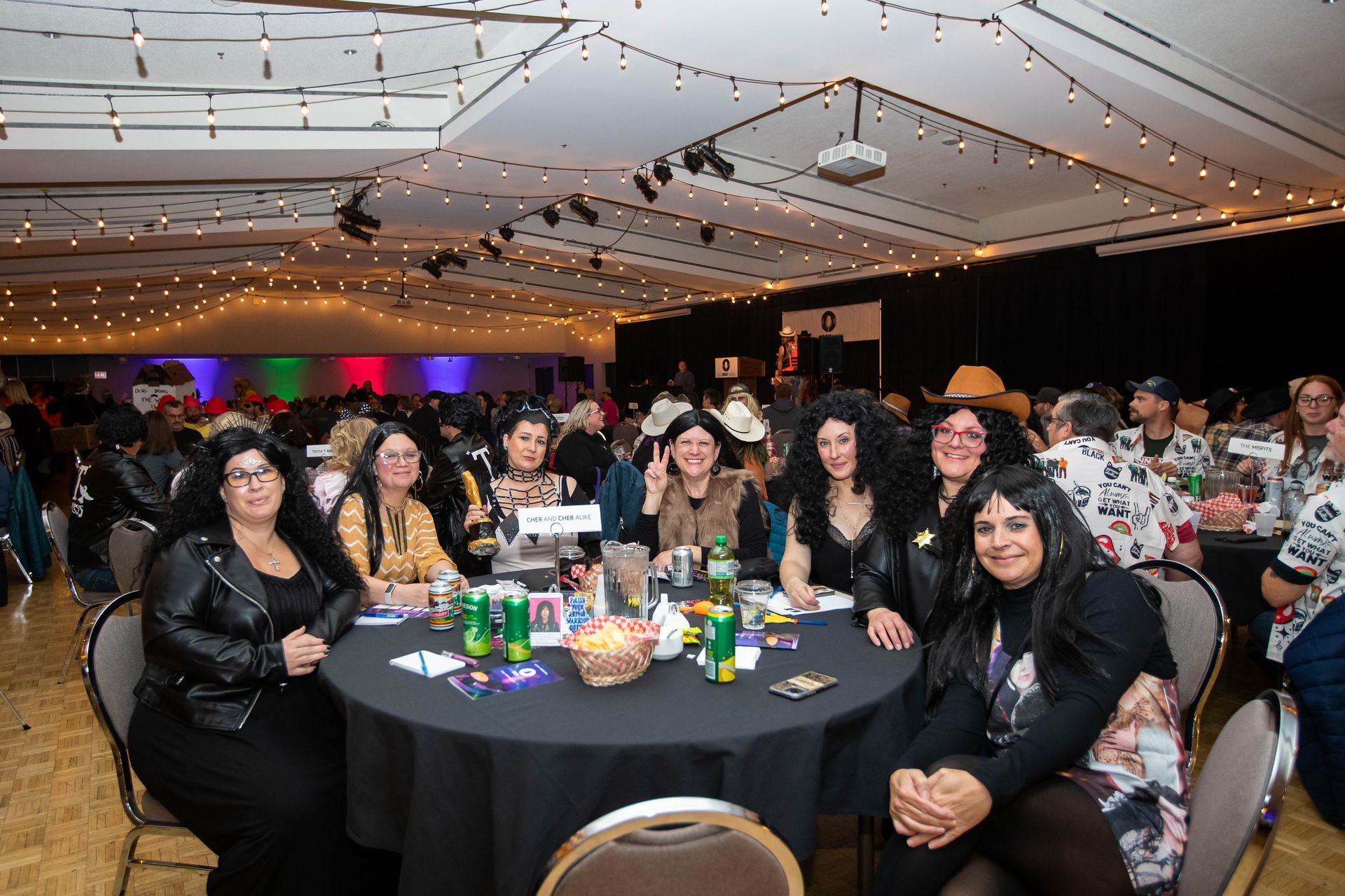 A group of women are sitting at a table in a large room.