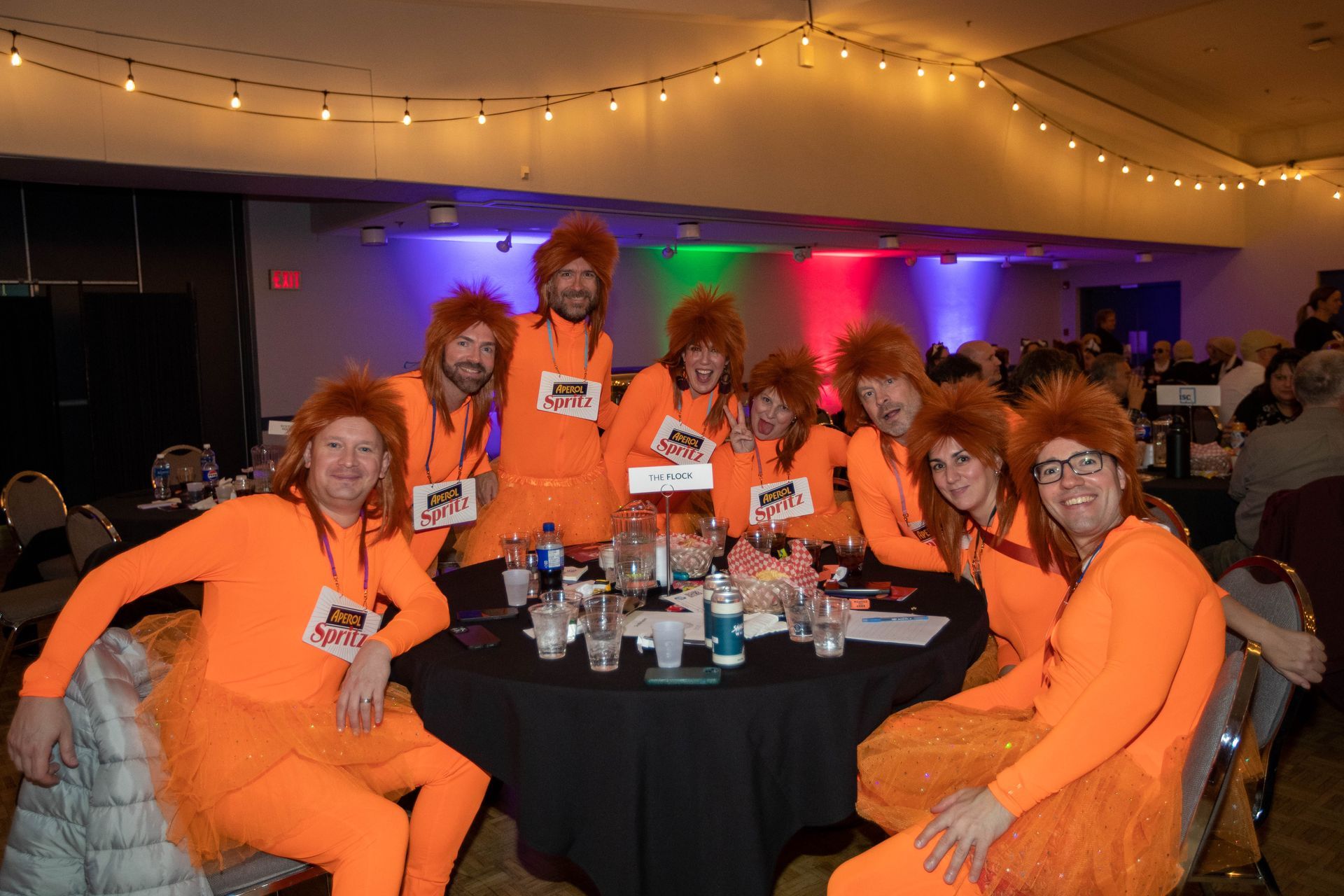 A group of people in orange costumes are sitting around a table.
