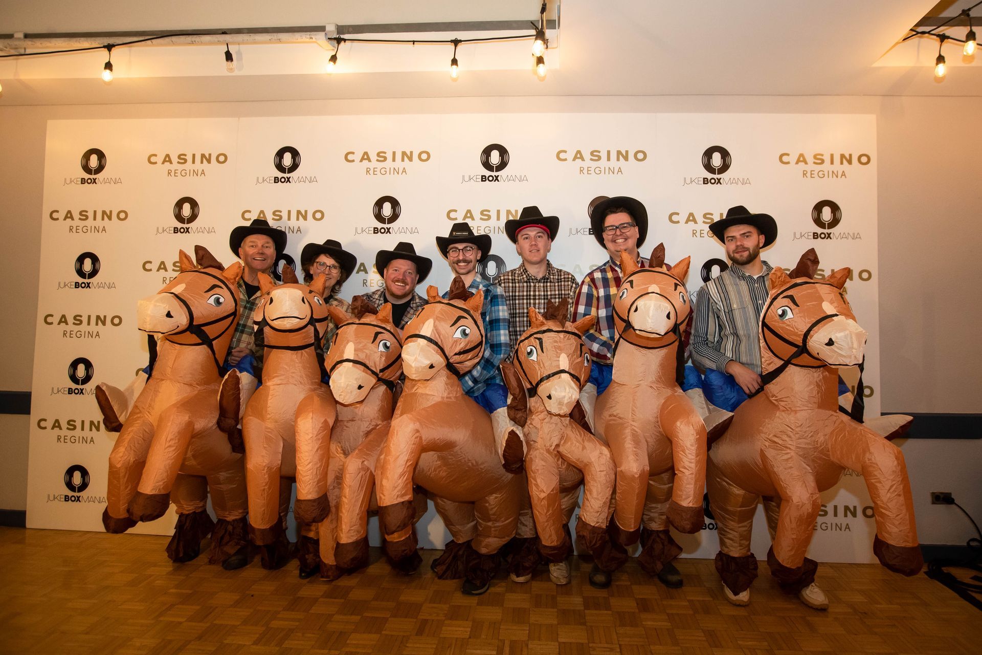 A group of men dressed as cowboys are standing next to inflatable horses.