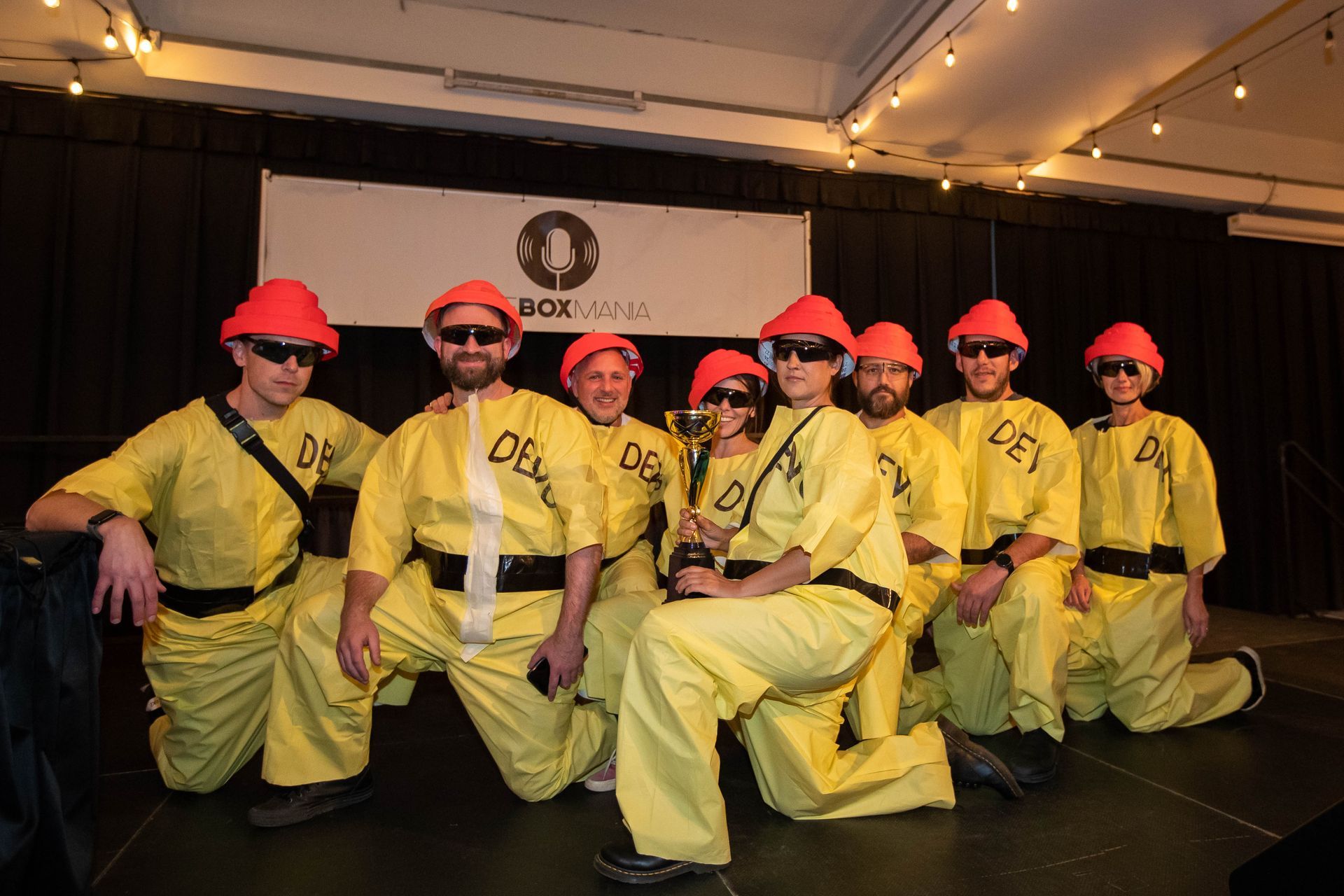 A group of men in yellow jumpsuits and hard hats pose for a picture