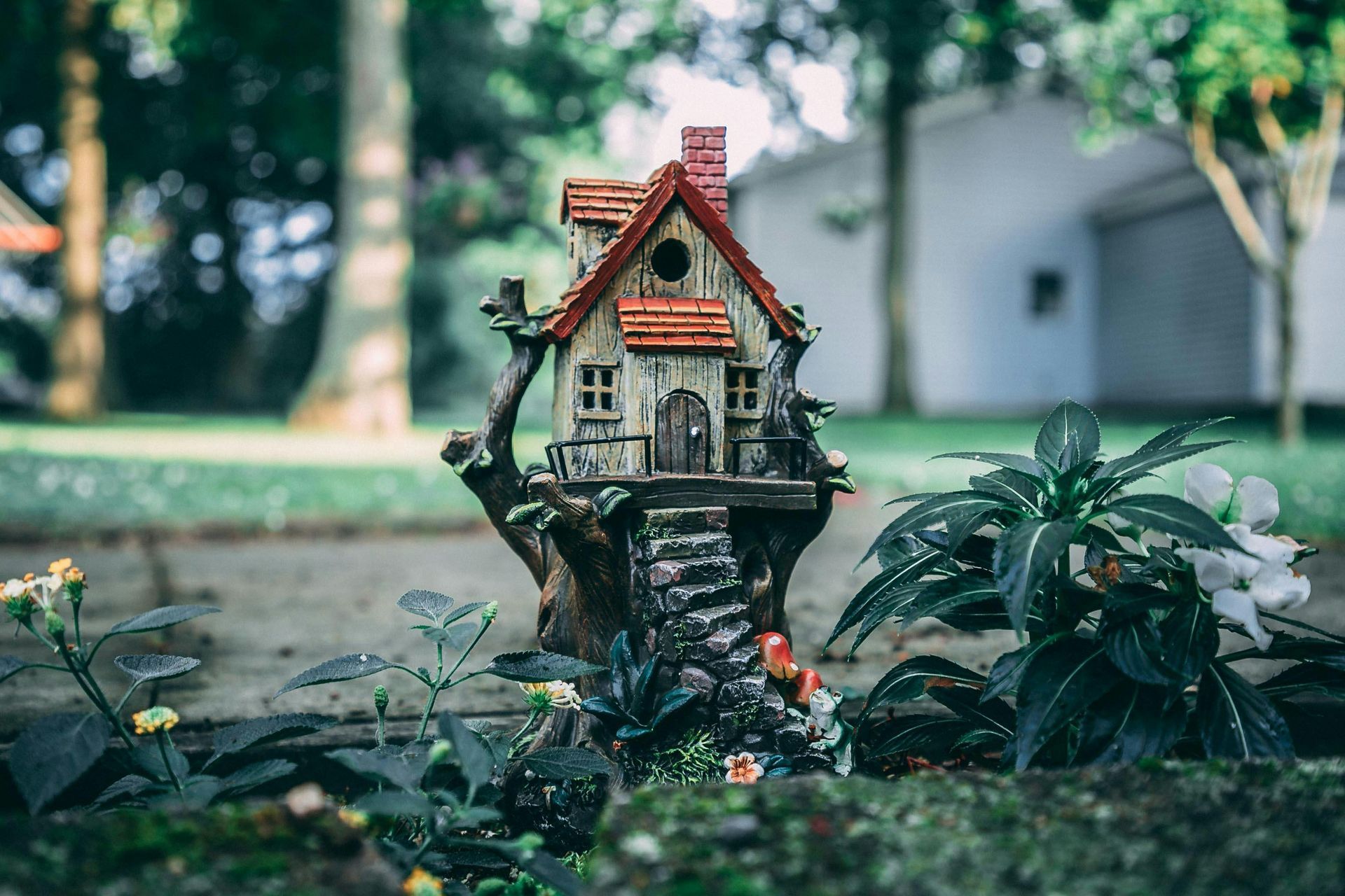 A small fairy house is sitting on top of a tree stump in a garden.