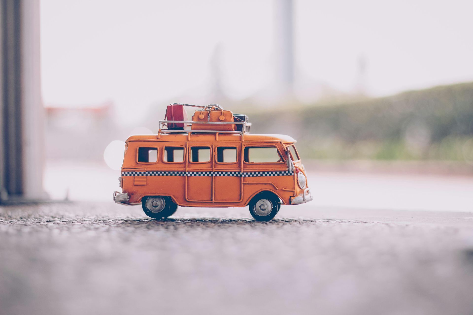 A toy bus with luggage on top of it is sitting on the ground.