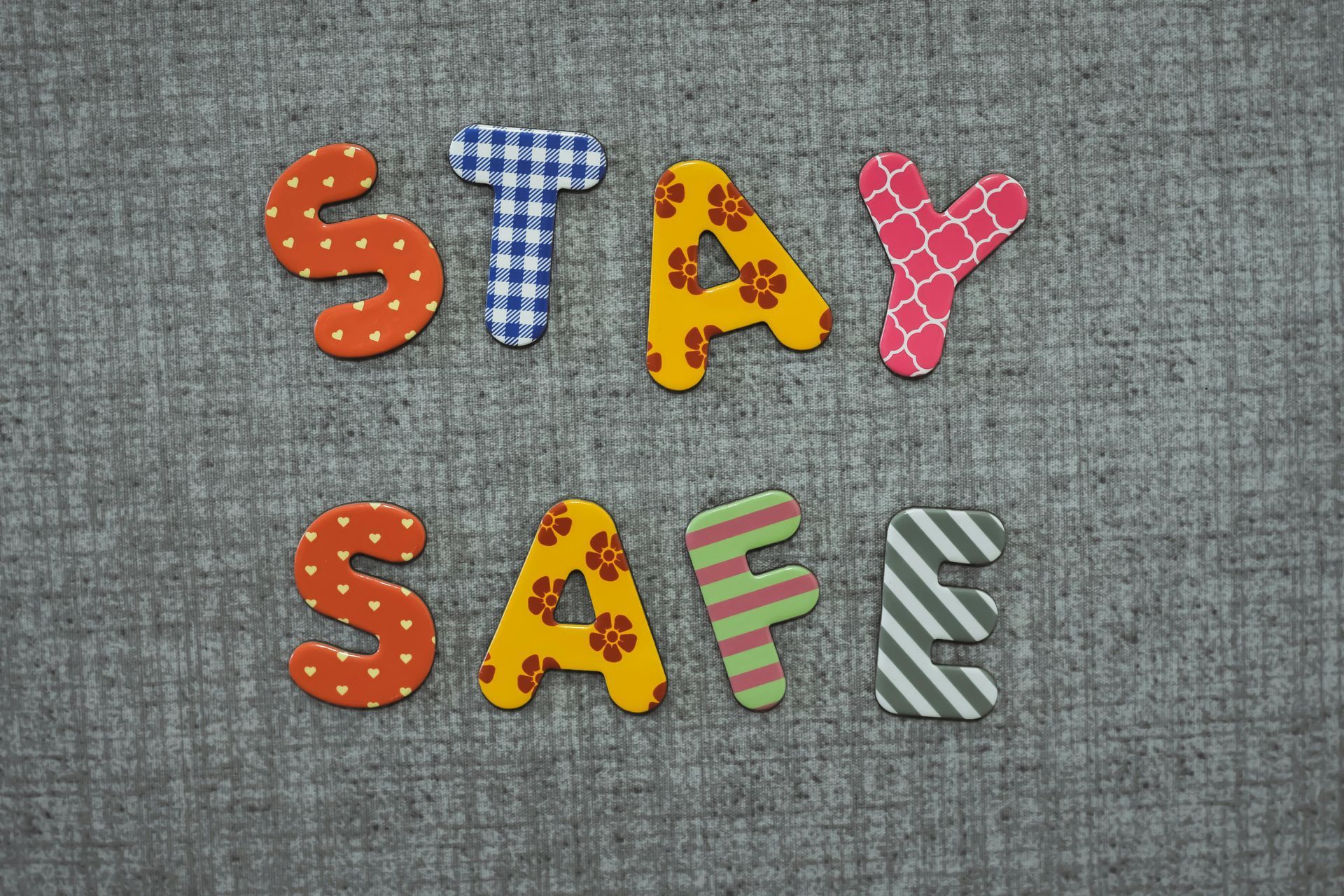 The word stay safe is written in colorful wooden letters on a gray background.