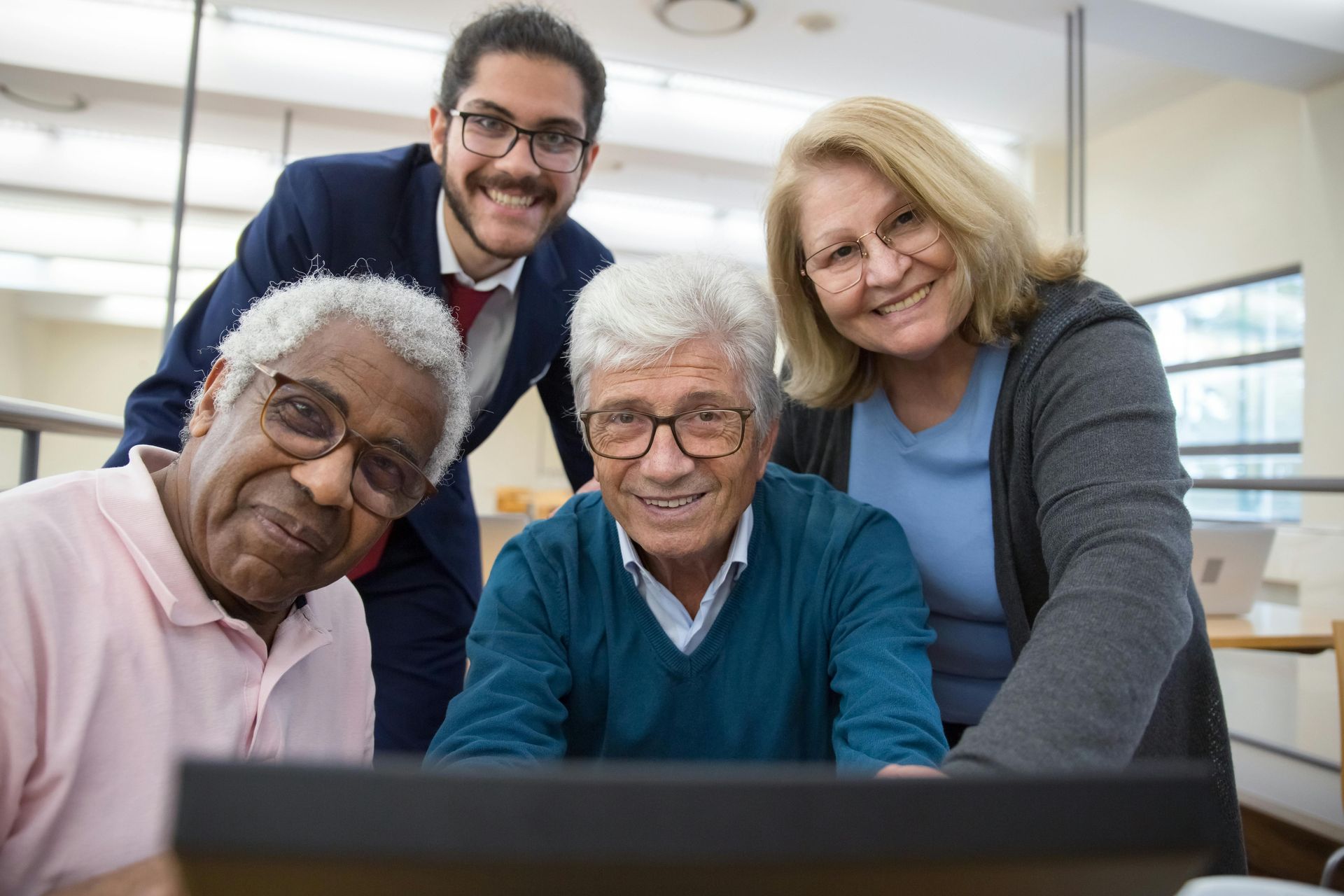 A group of older people are looking at a laptop computer.