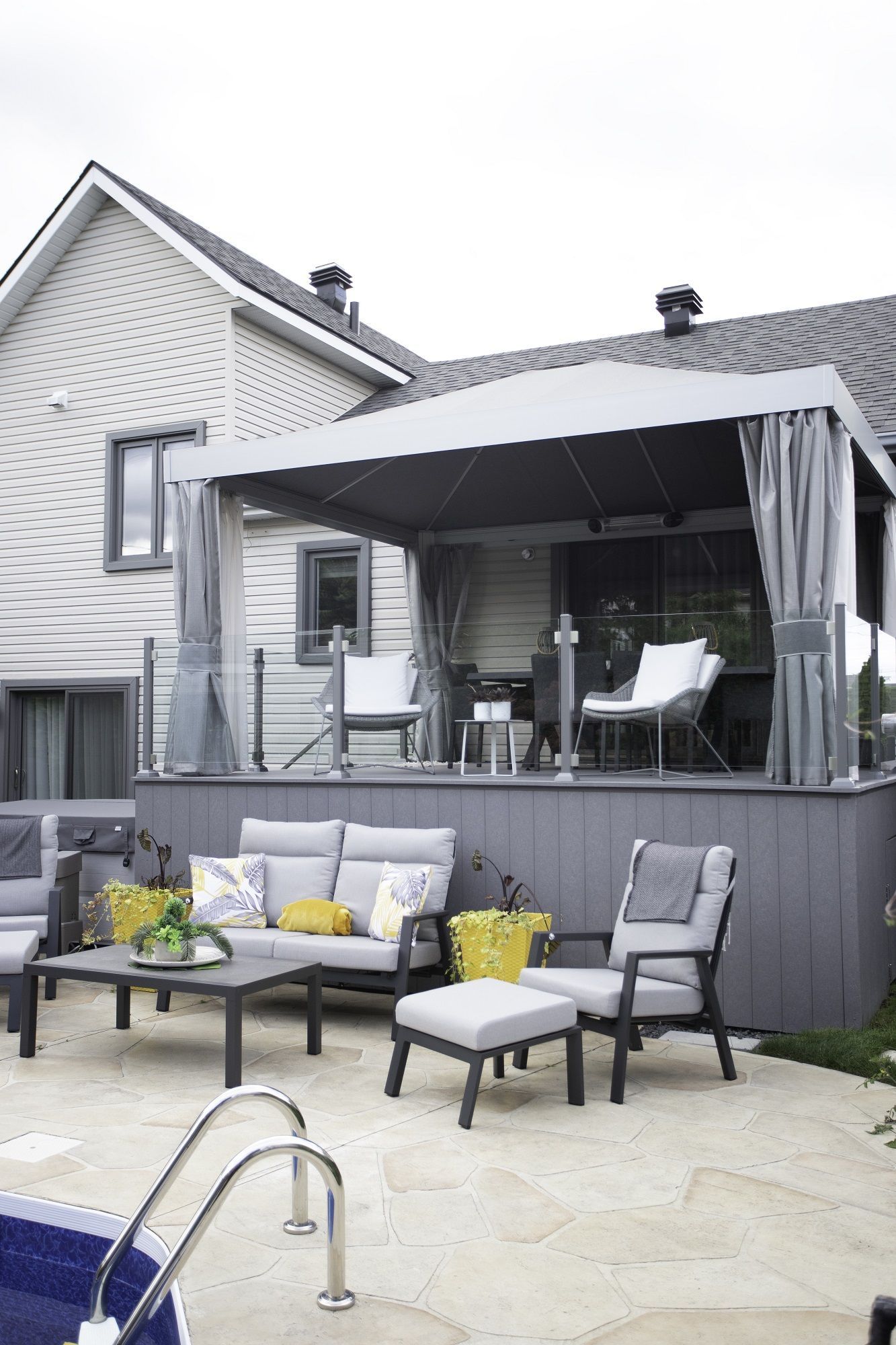 Un patio avec un auvent au-dessus et une piscine devant une maison.