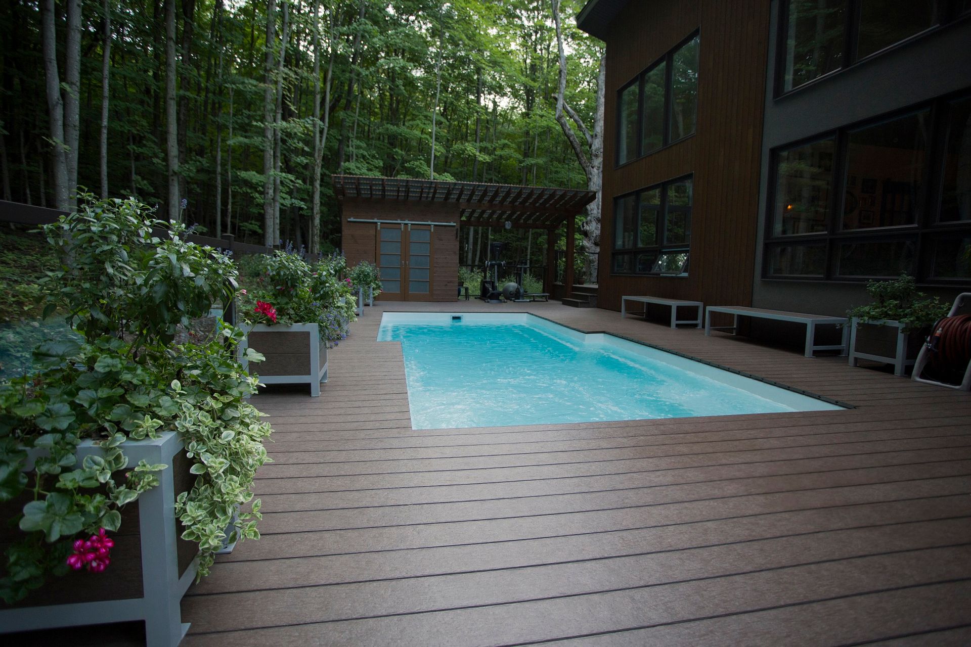 Une grande piscine est entourée d'une terrasse en bois.