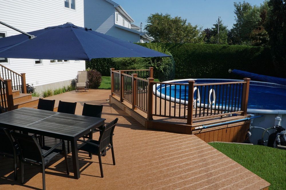 Un patio avec une table et des chaises à côté d'une piscine