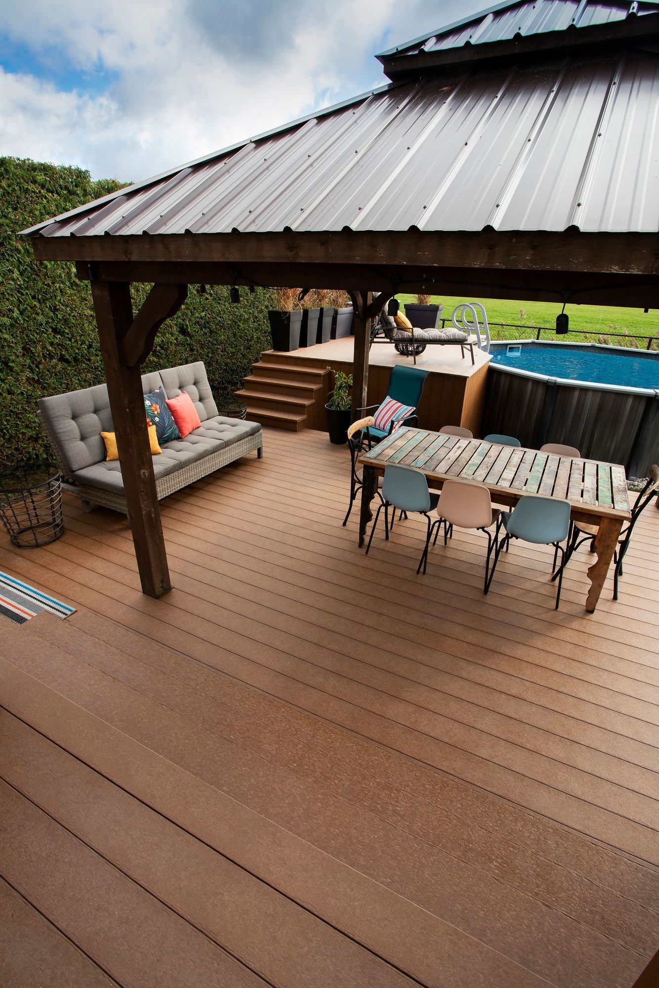 Une terrasse en bois avec une table et des chaises sous un gazebo.