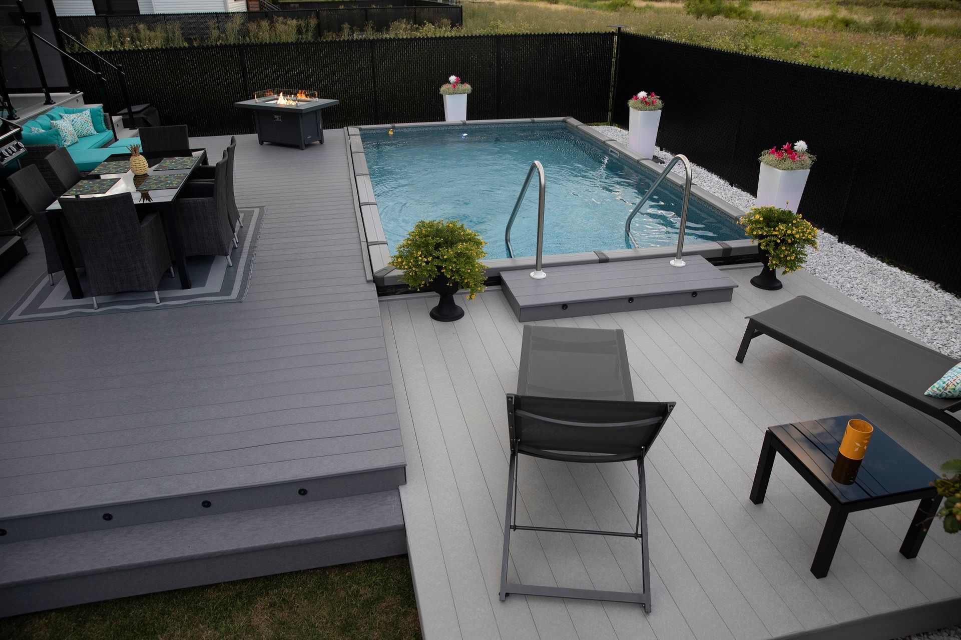Une grande piscine est entourée d'une terrasse avec chaises et tables.