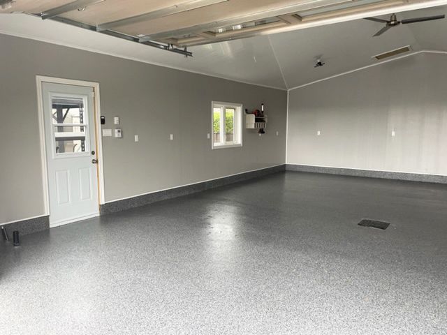 Un garage vide avec un sol gris et une porte blanche.