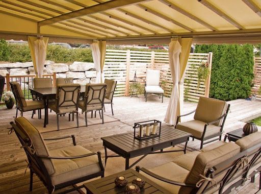 Un patio avec une table et des chaises sous un auvent