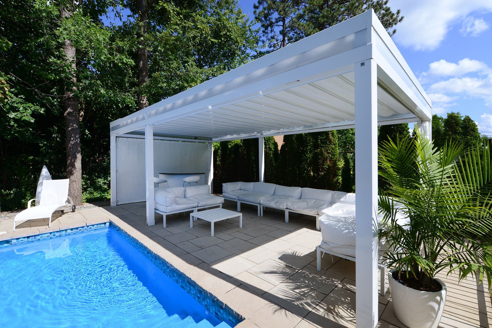 Une pergola blanche se trouve à côté d'une piscine