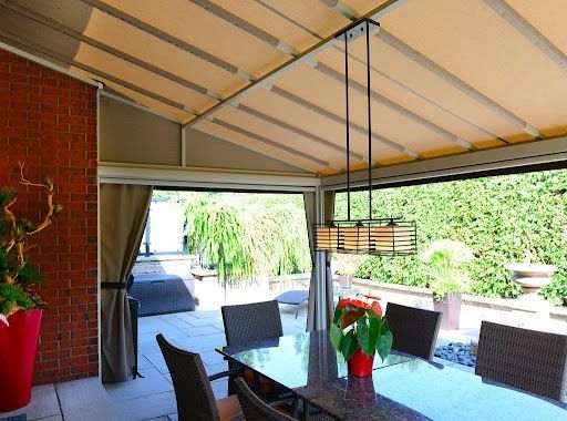 Une salle à manger avec une table et des chaises sous un auvent.