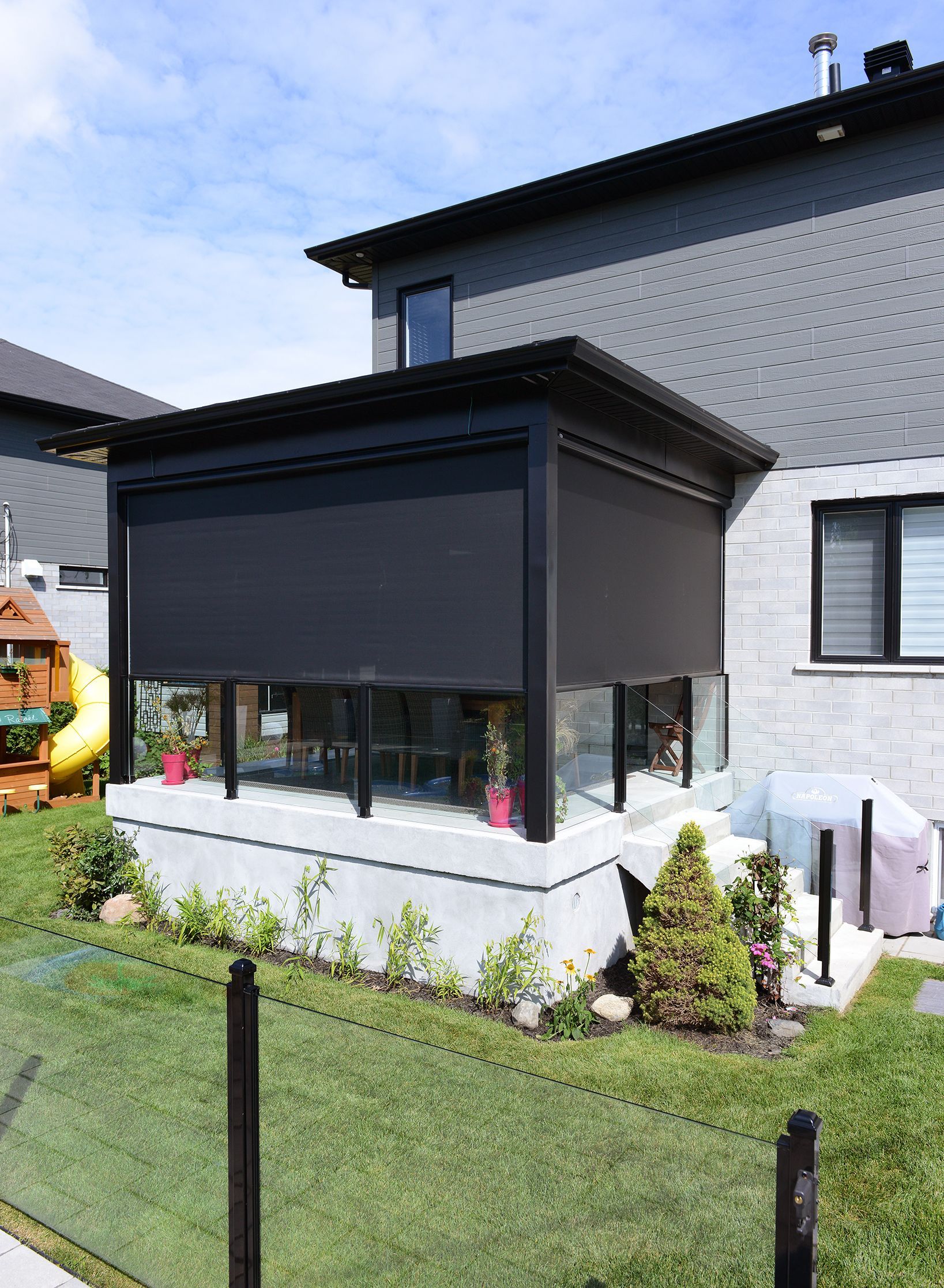 Une maison avec une véranda et une aire de jeux dans la cour.