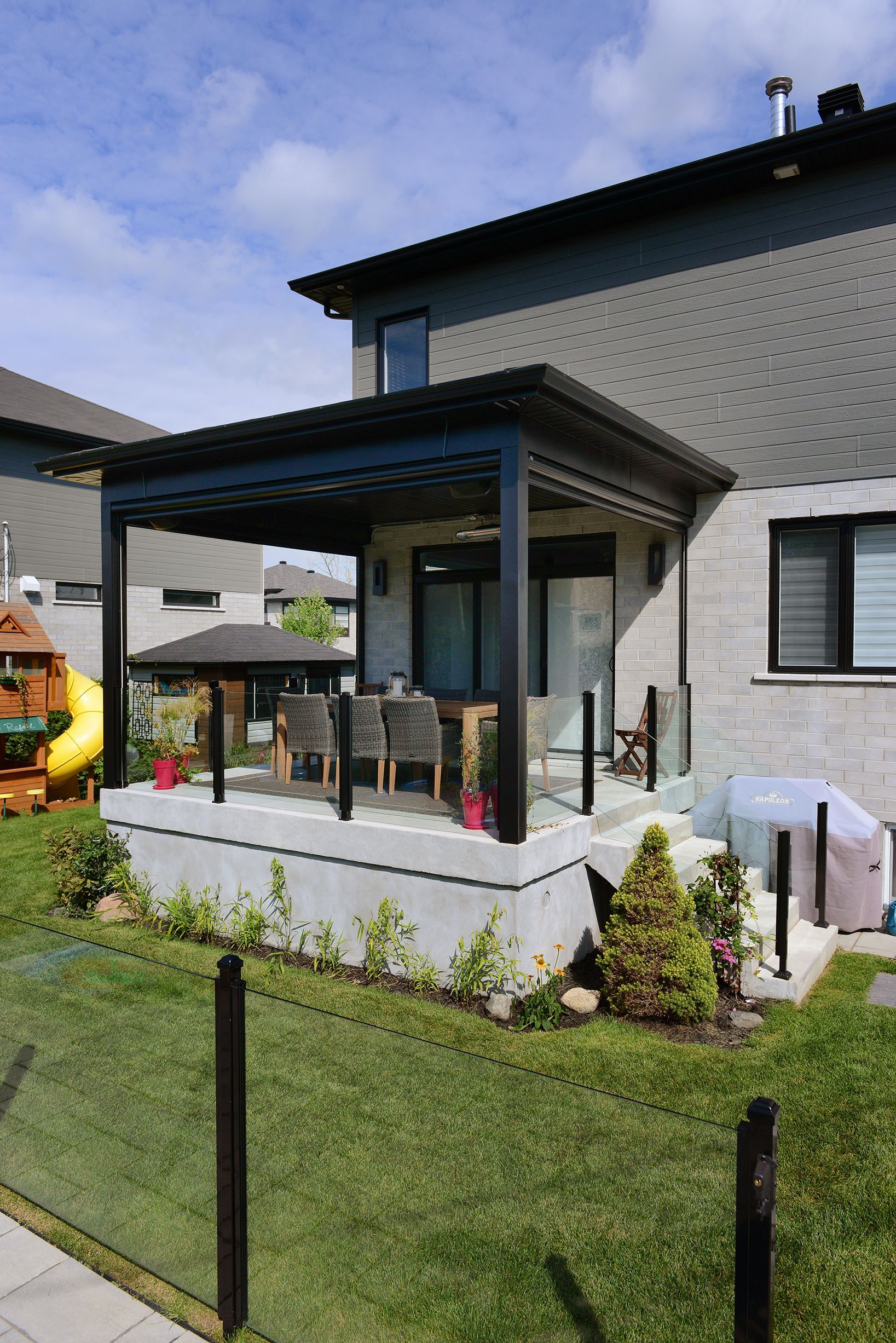 Une maison avec un porche et une aire de jeux dans la cour.