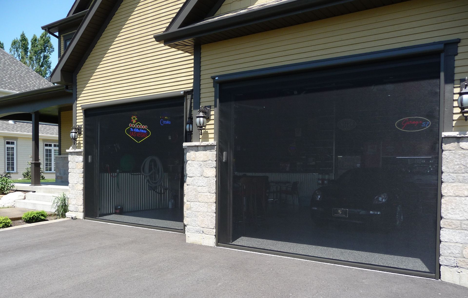 Une maison avec deux portes de garage noires et une enseigne au néon qui dit ouvert