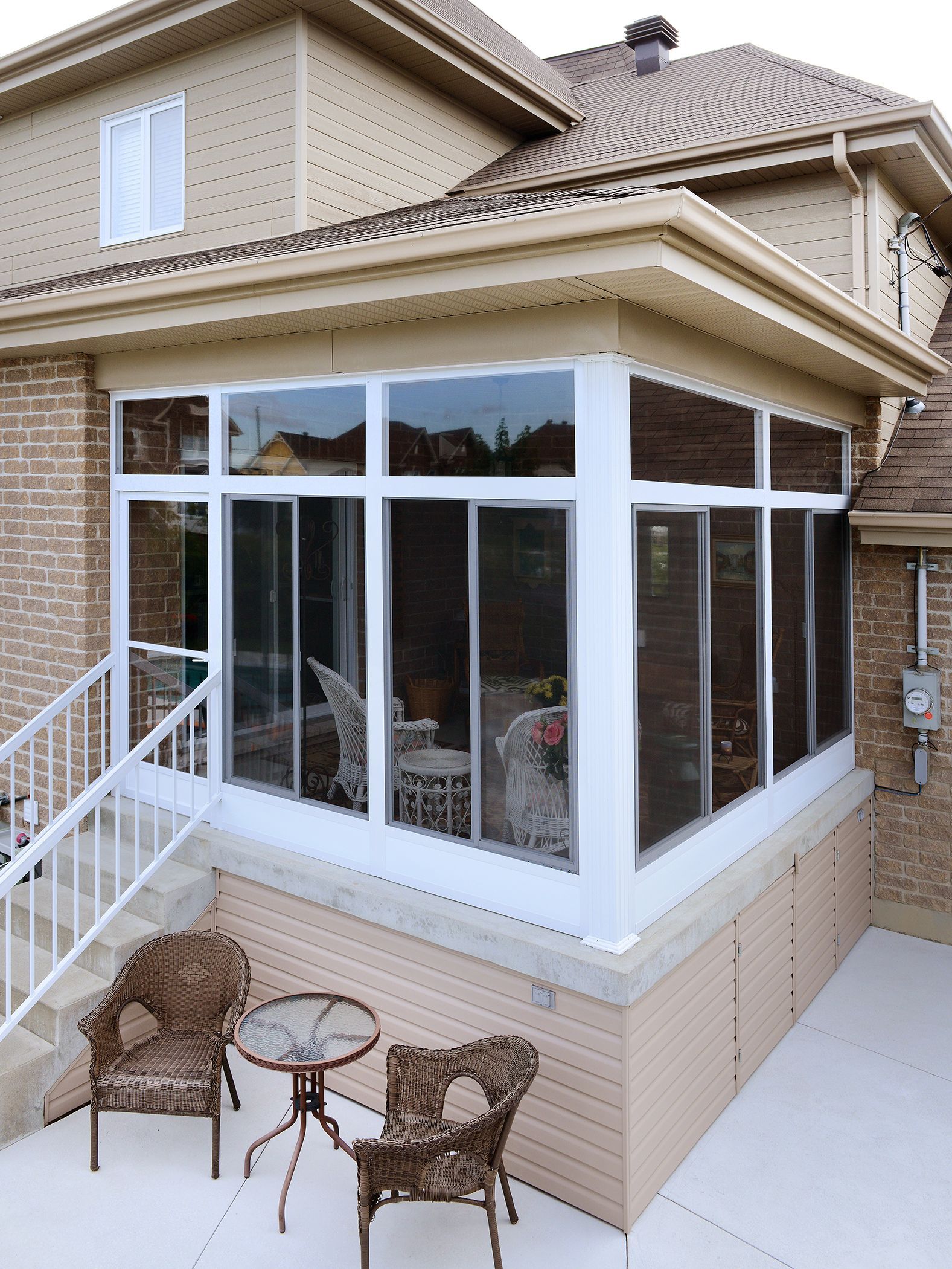 Une maison avec une véranda avec des chaises et une table