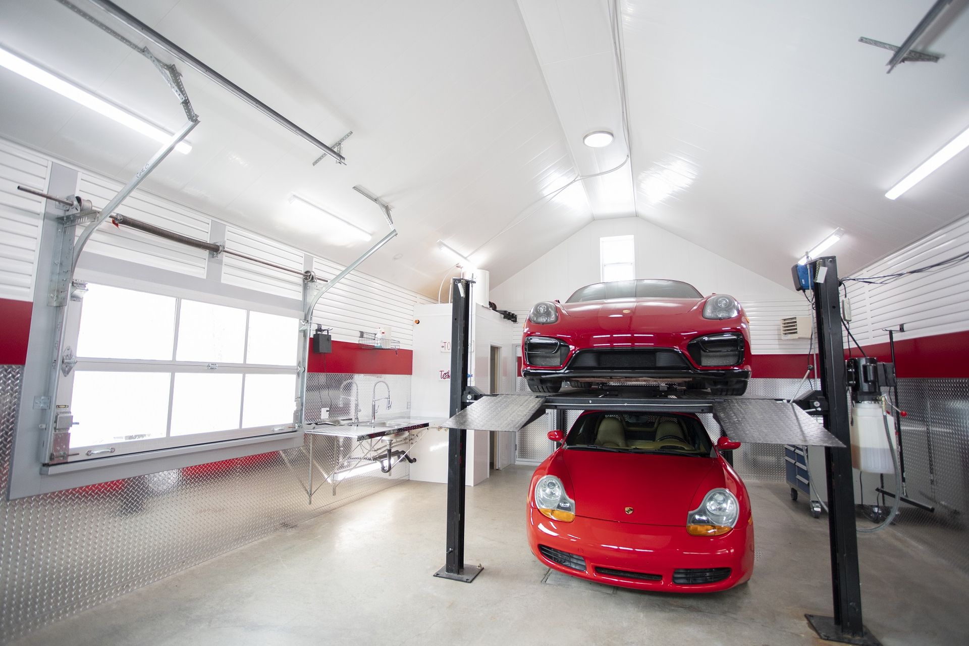 Une voiture rouge est sur un ascenseur dans un garage.