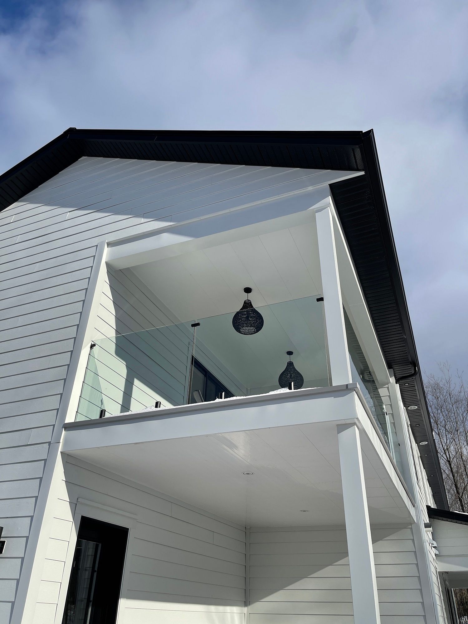 Une maison blanche avec un balcon et une balustrade en verre