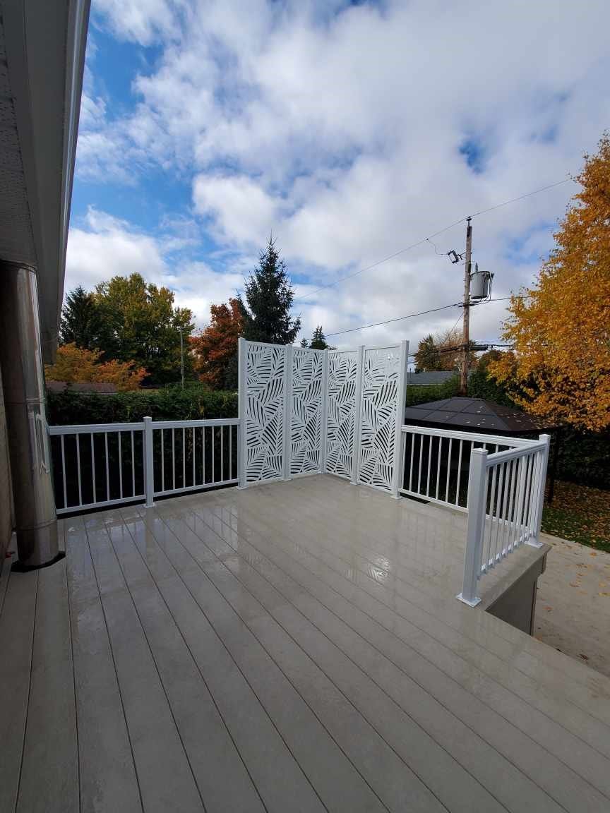 Une grande terrasse avec une balustrade blanche et un écran blanc.