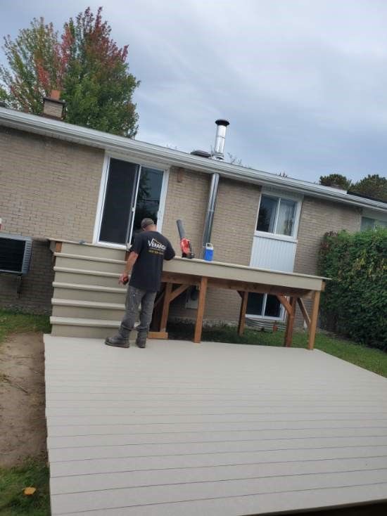 Un homme debout sur une terrasse devant une maison