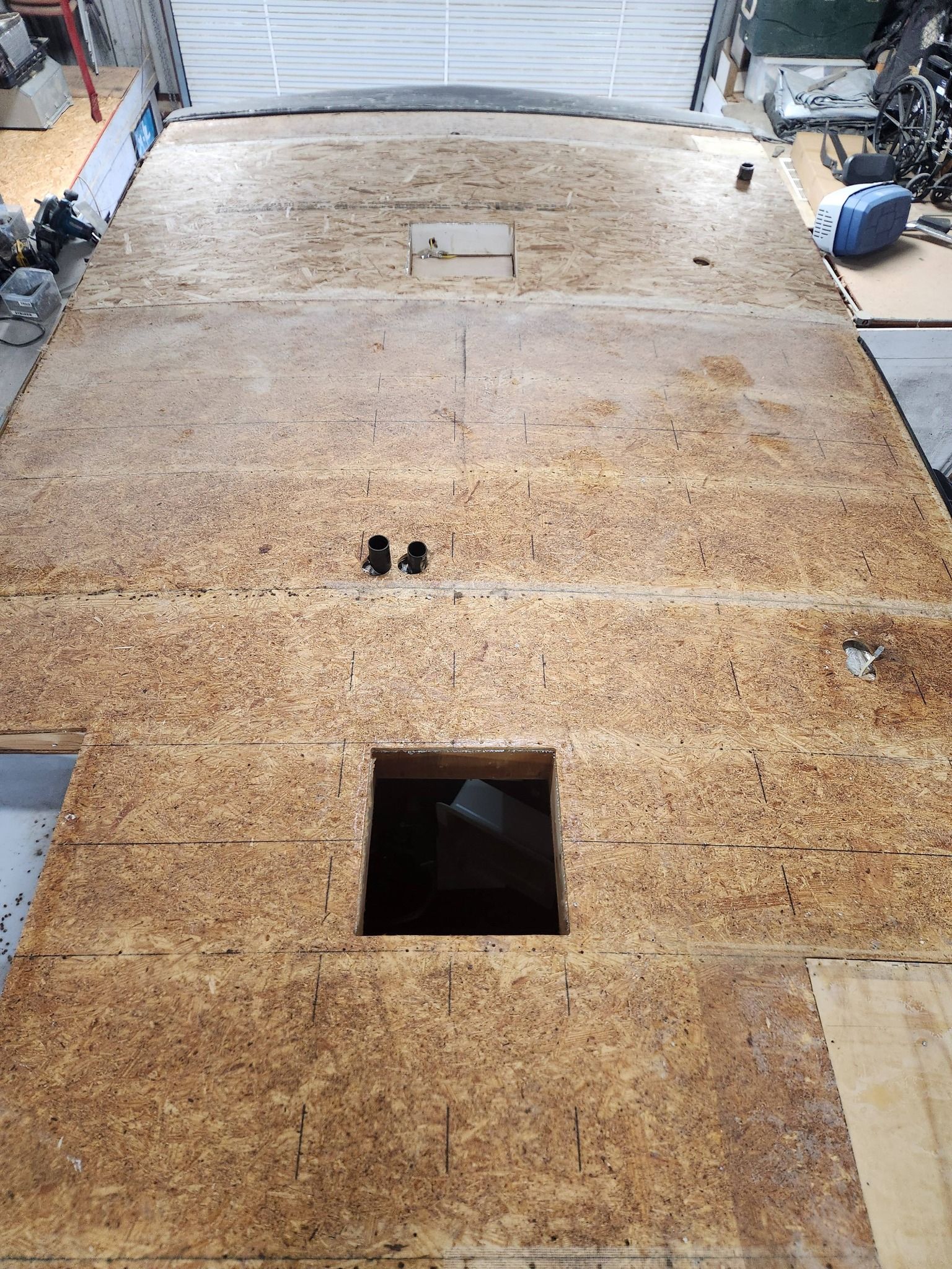 Wooden floor panels in a garage, with a square cutout and a small hatch near the center.