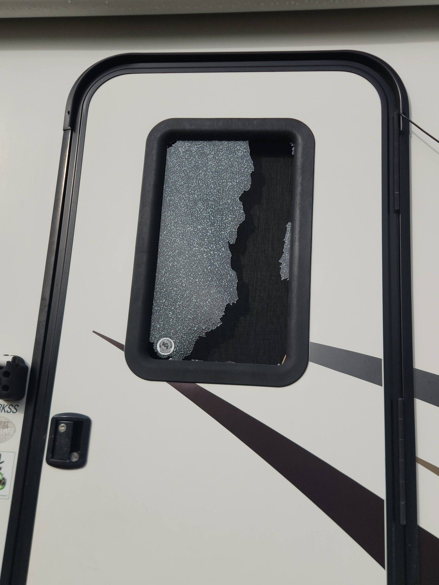 Cracked window on a trailer door, with shattered glass in the upper pane.