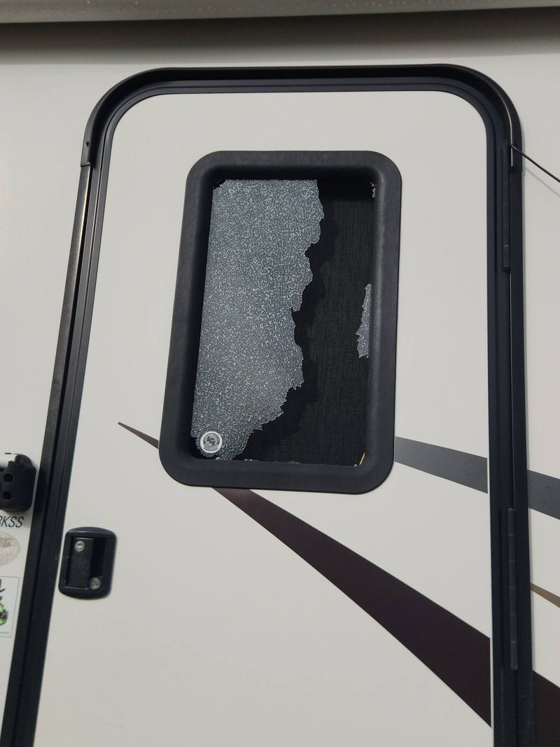 Broken RV window with shattered glass on a camper door.