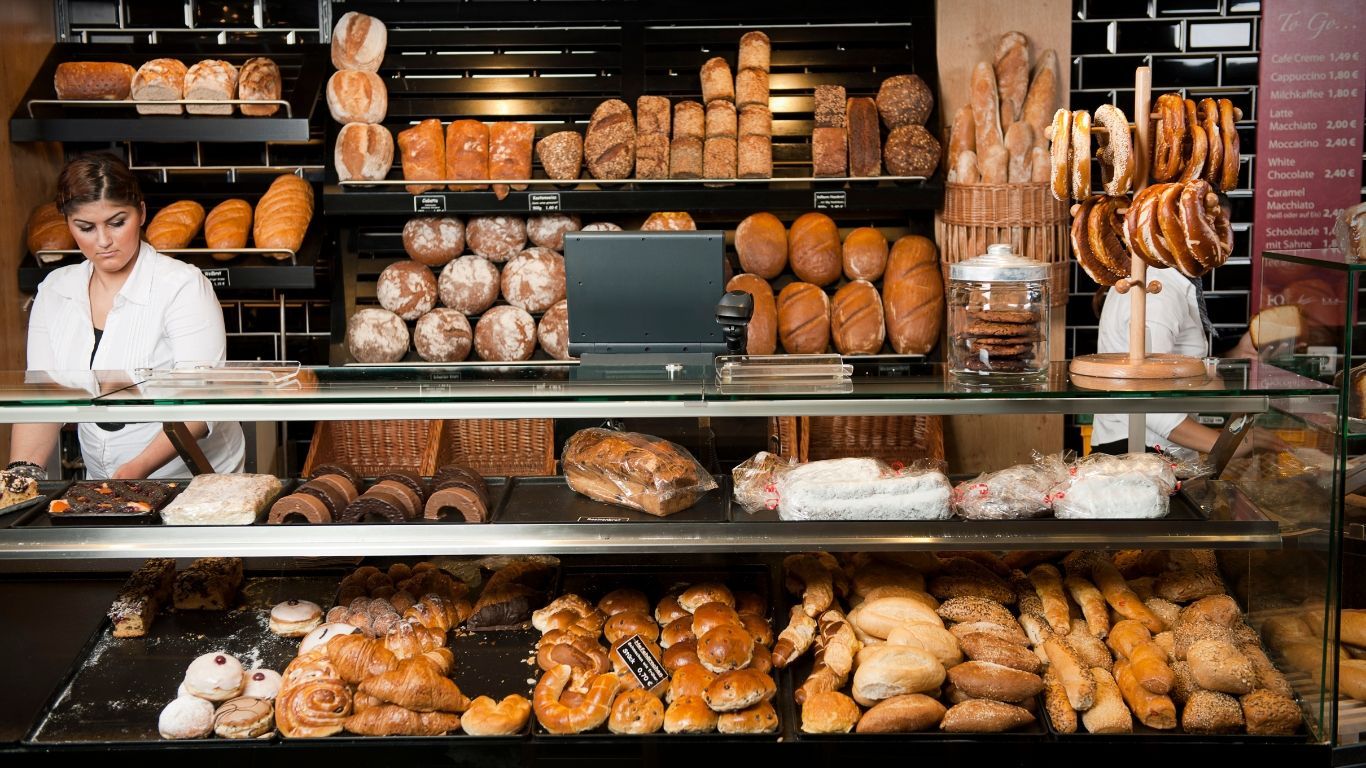 Una donna è in piedi dietro una vetrina in una panetteria.