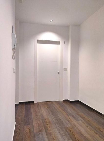 Una mano che mescola un cappuccino schiumoso in una tazza nera Mado, un croissant e dei bicchieri d'acqua su un tavolo.