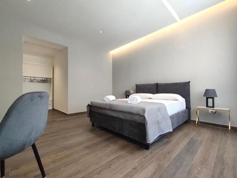 Una mano che mescola un cappuccino schiumoso in una tazza nera Mado, un croissant e dei bicchieri d'acqua su un tavolo.