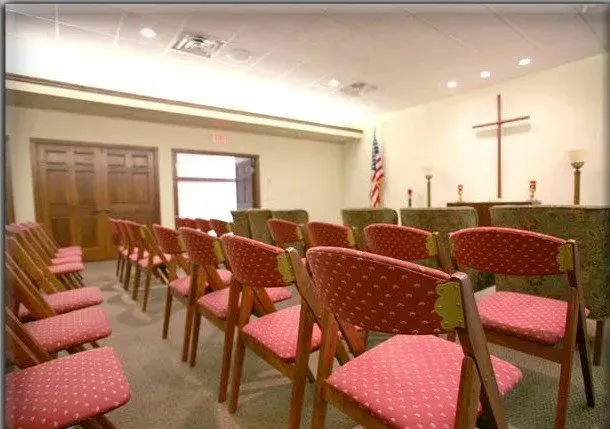 Rows of red chairs in a church with a cross in the background