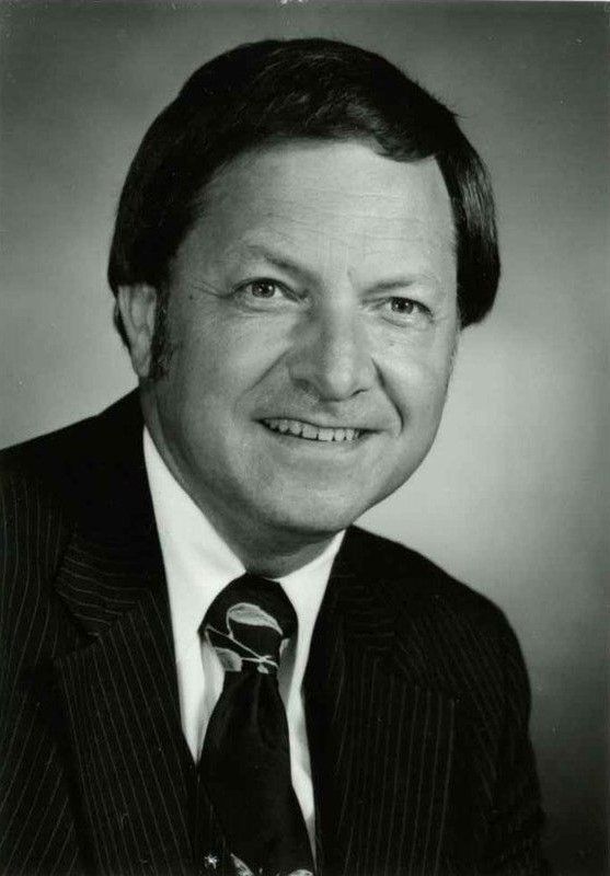 A man in a suit and tie is smiling for the camera