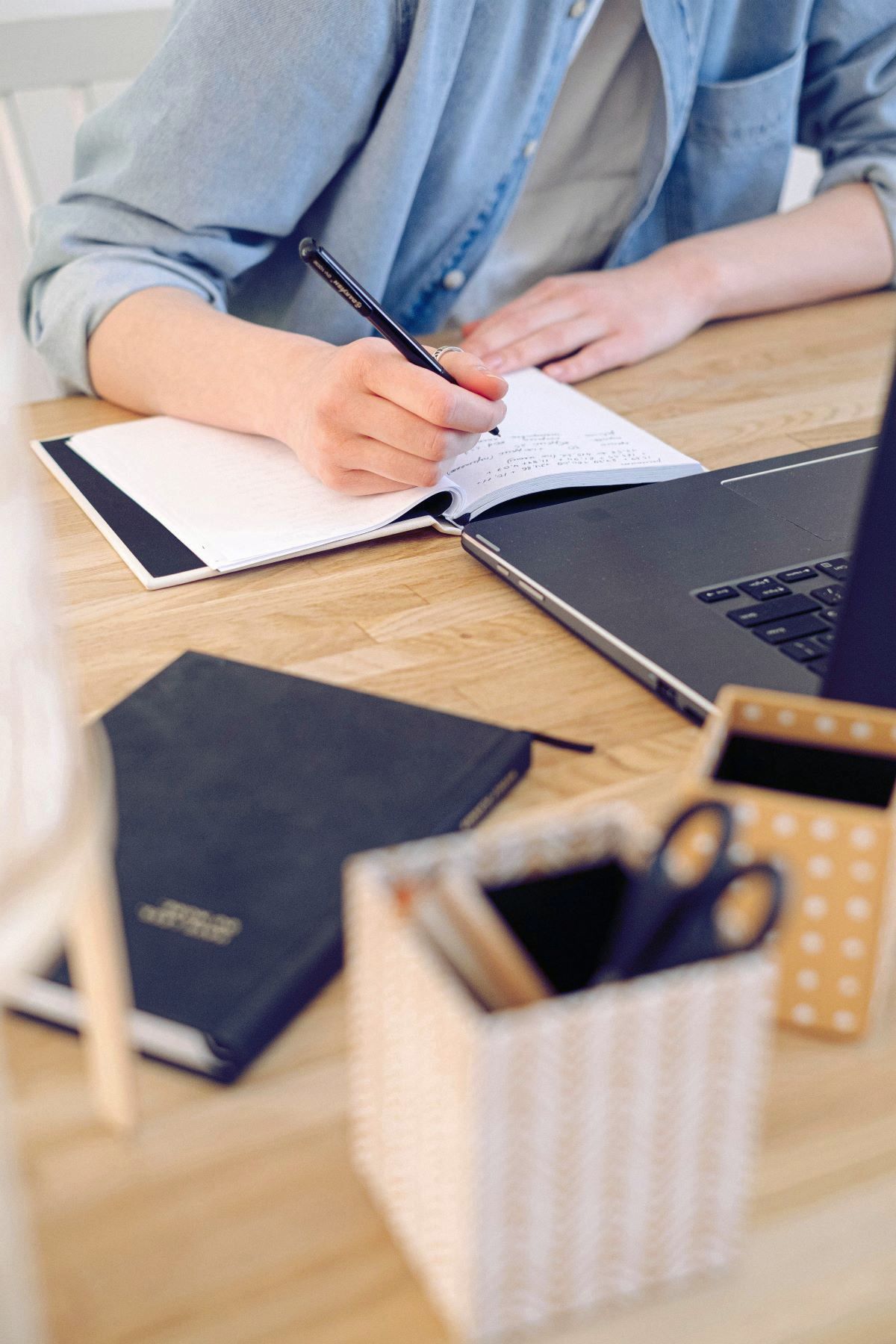 A person is sitting at a desk writing in a notebook.