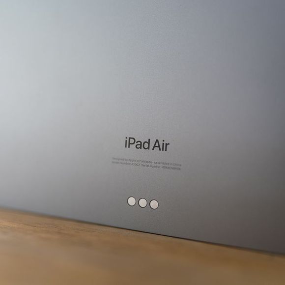 The back of an ipad air is shown on a wooden table.