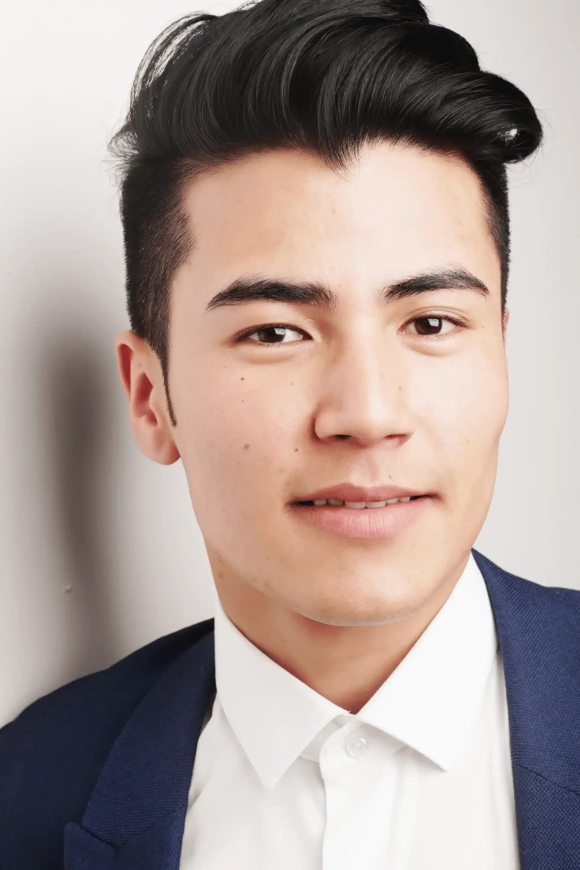 a man wearing a white shirt and a blue jacket looks at the camera