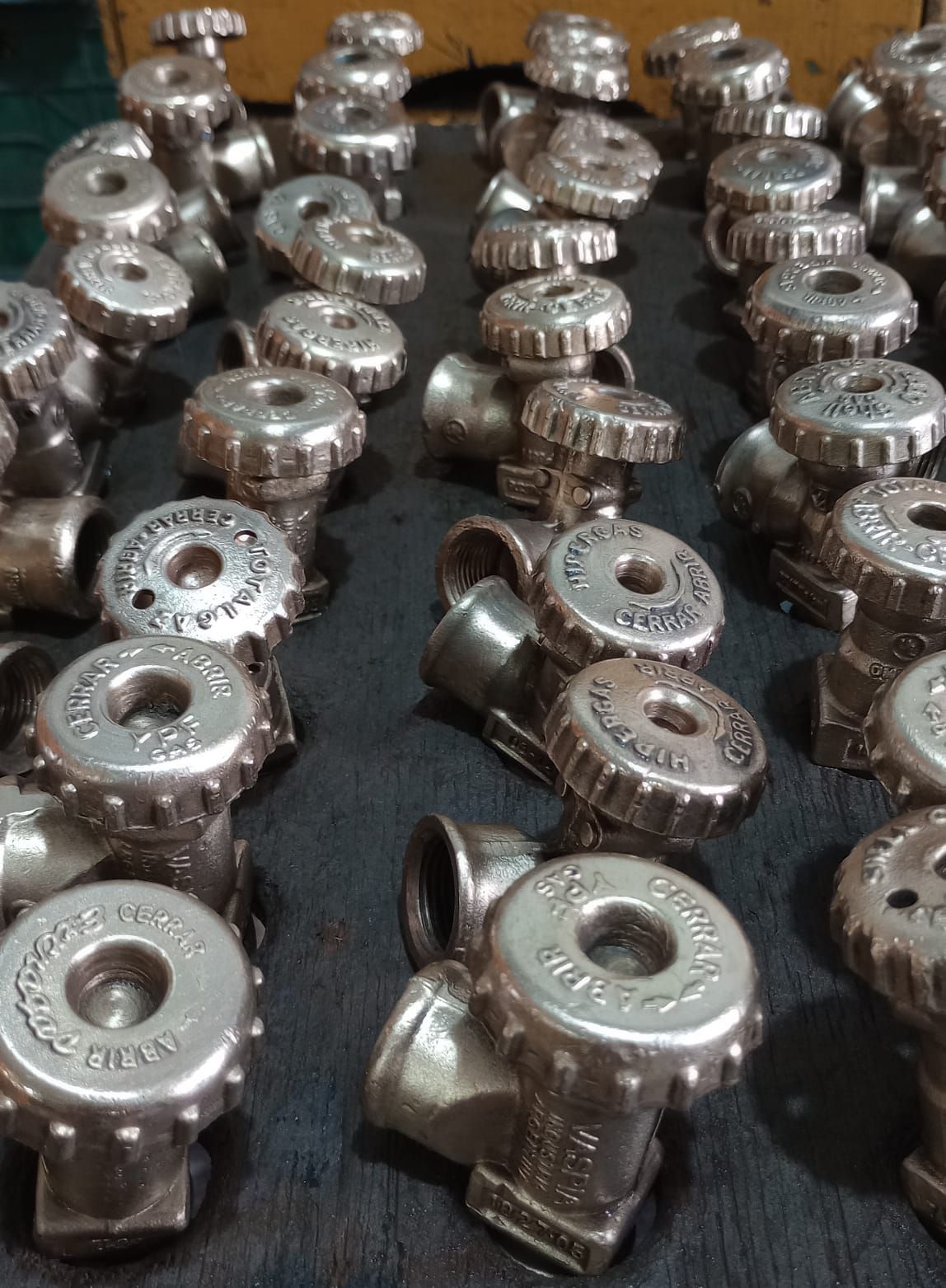 Primer plano de muchas válvulas de color plateado con perillas, dispuestas sobre una superficie oscura.