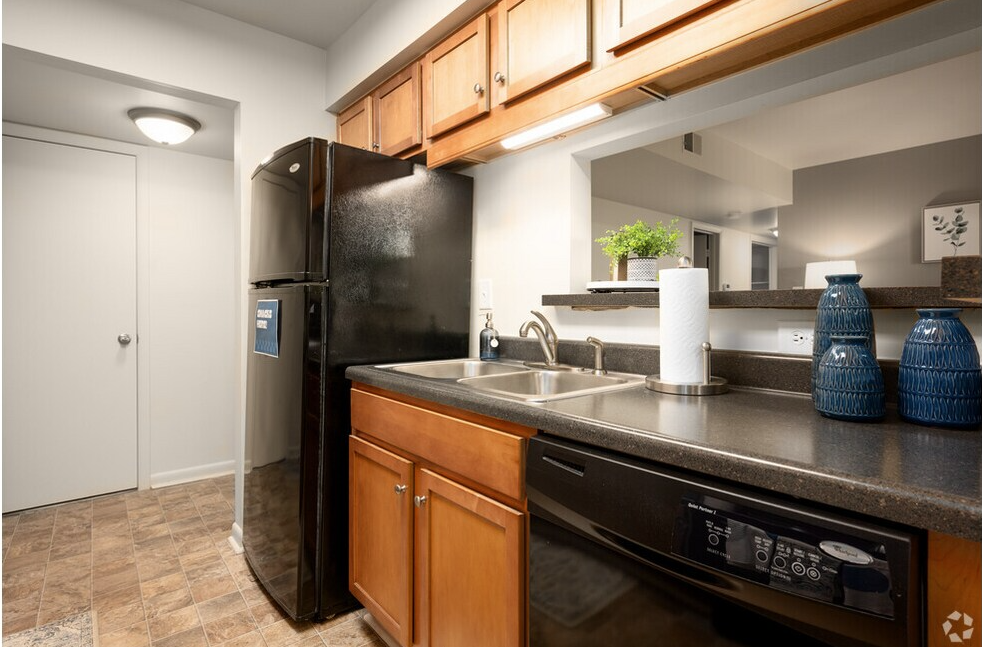 Kitchen with black appliances, wooden cabinets, and a countertop with a sink.