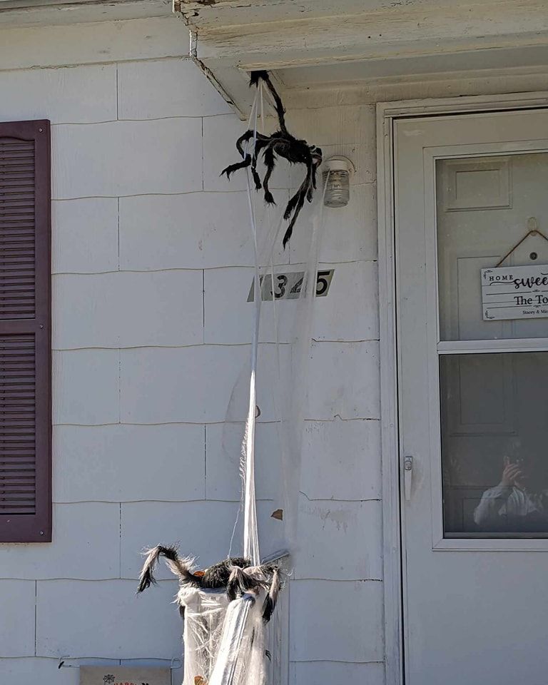 Halloween spider decorations hang from a house.