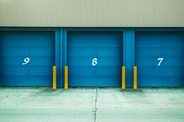 Blue storage unit doors numbered 9, 8, and 7 with yellow bumpers, in a row.