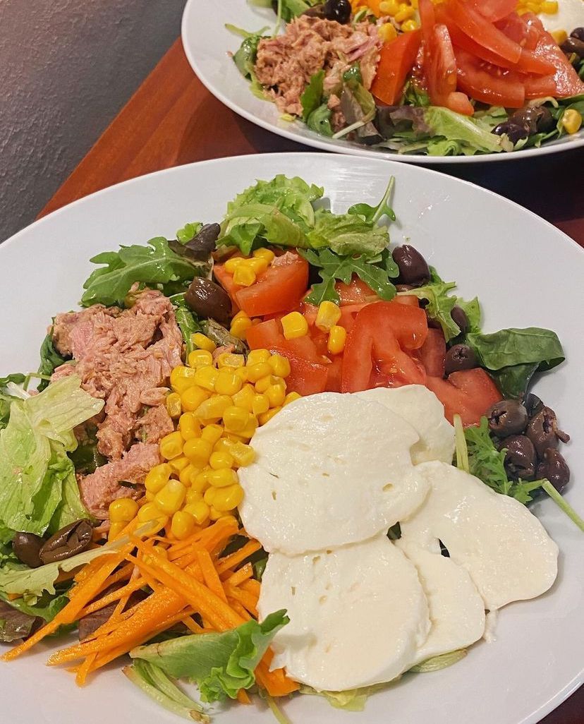 Un piatto bianco con sopra un'insalata di verdure e carne