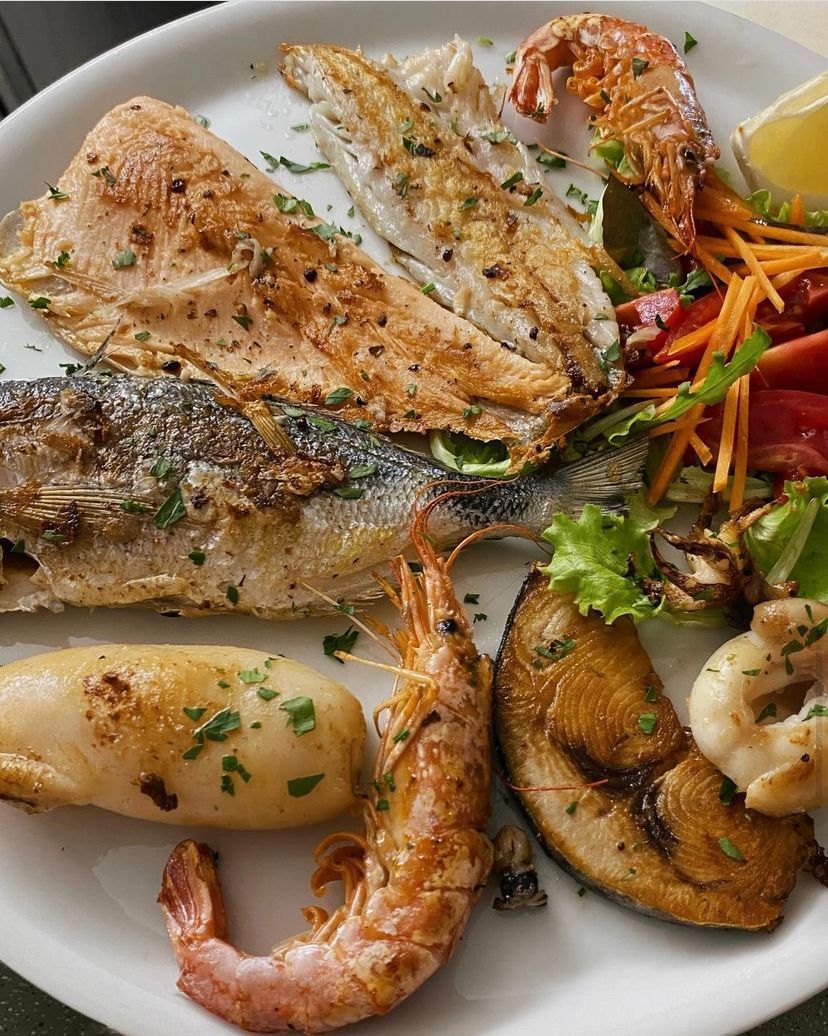 Un piatto bianco guarnito con una varietà di frutti di mare e verdure.